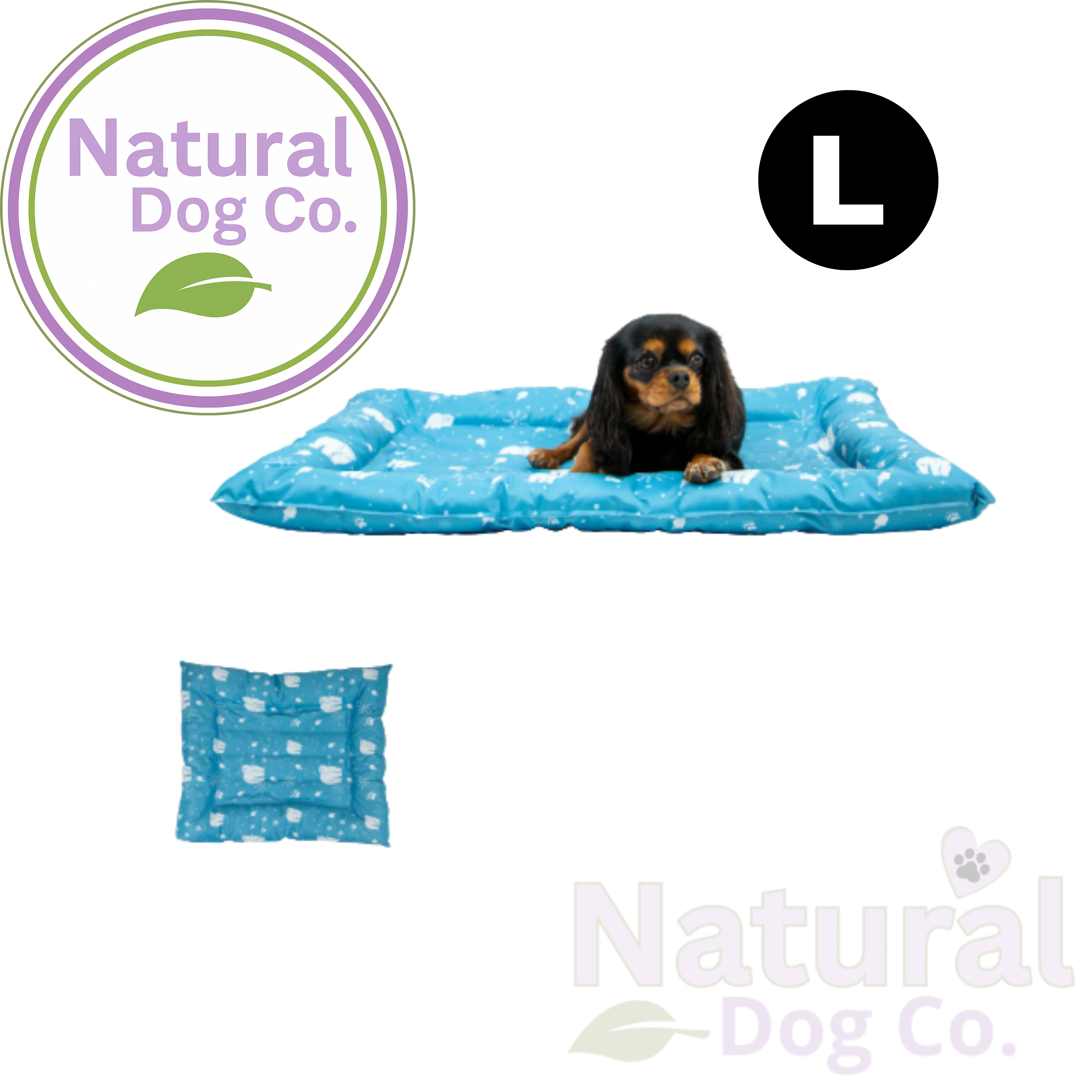 A small black and tan dog lies on a blue rectangular pet bed with a white paw print pattern. The image includes a circular 'L' size marker, a small inset of the bed's underside, and the Natural Dog Co.