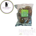 A clear plastic bag of southcliffe pig ear dog treats with a green product label. The image includes a circular '12 Weeks + Recommended' badge on the top left and a 'Natural Dog Co